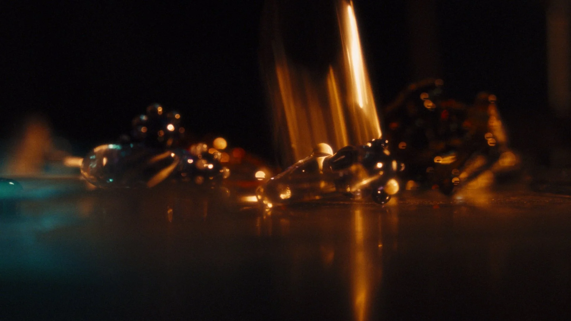 Close-up of shattered glass beads and a streak of light against a dark background.