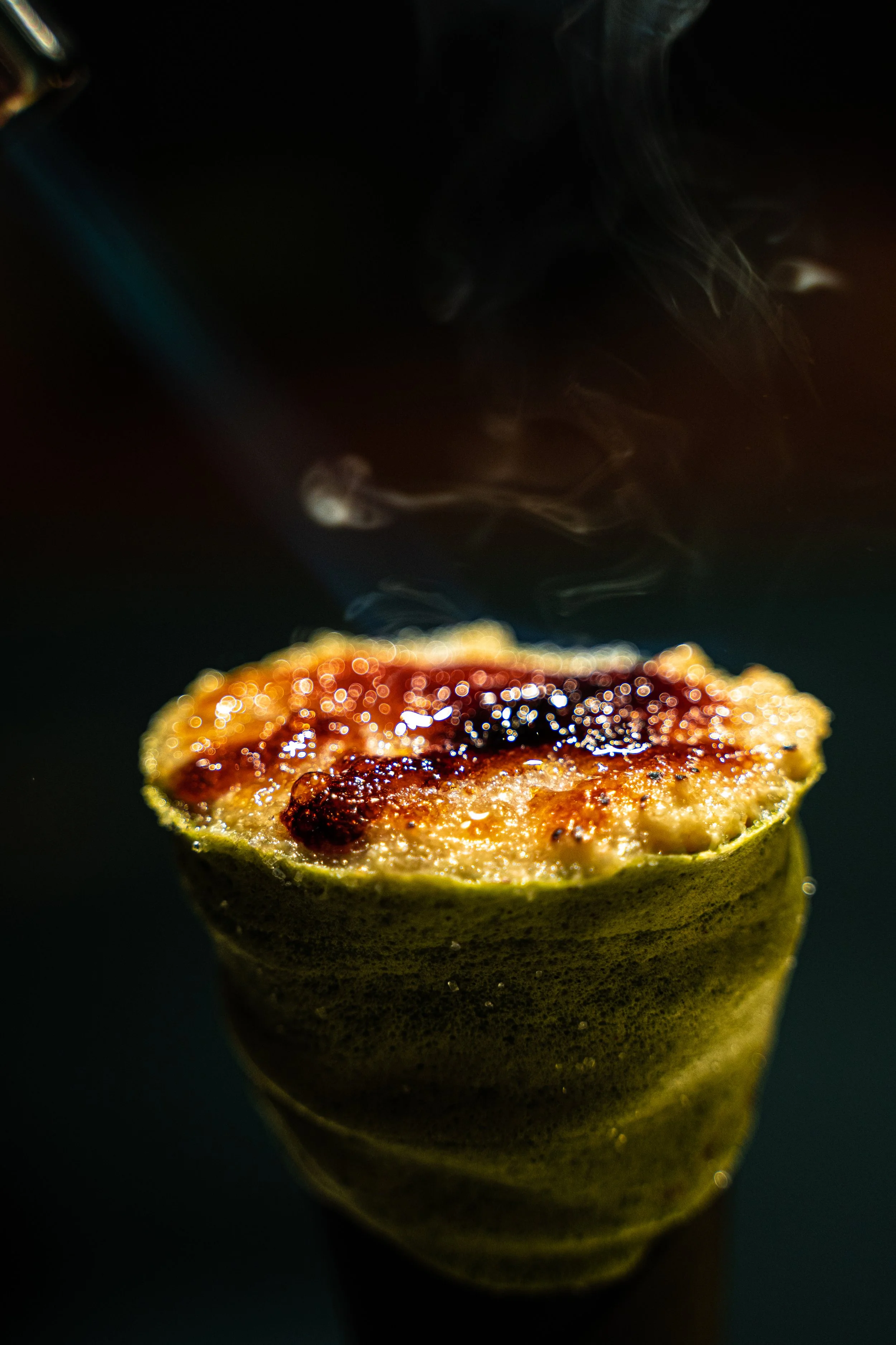 Close-up of a lit matchstick head, with some smoke rising from it against a dark background.