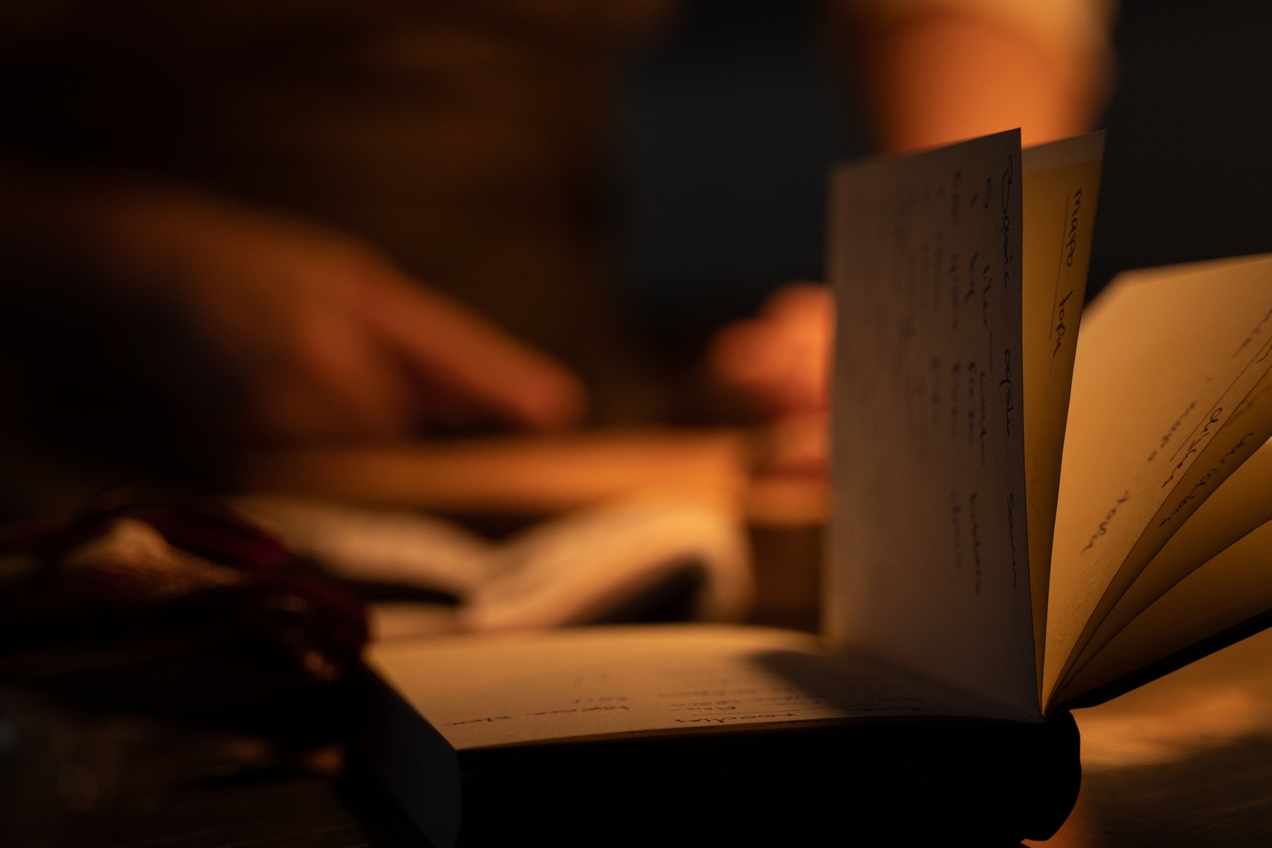 Close-up of a person flipping through pages of a notebook or journal in warm, dim lighting