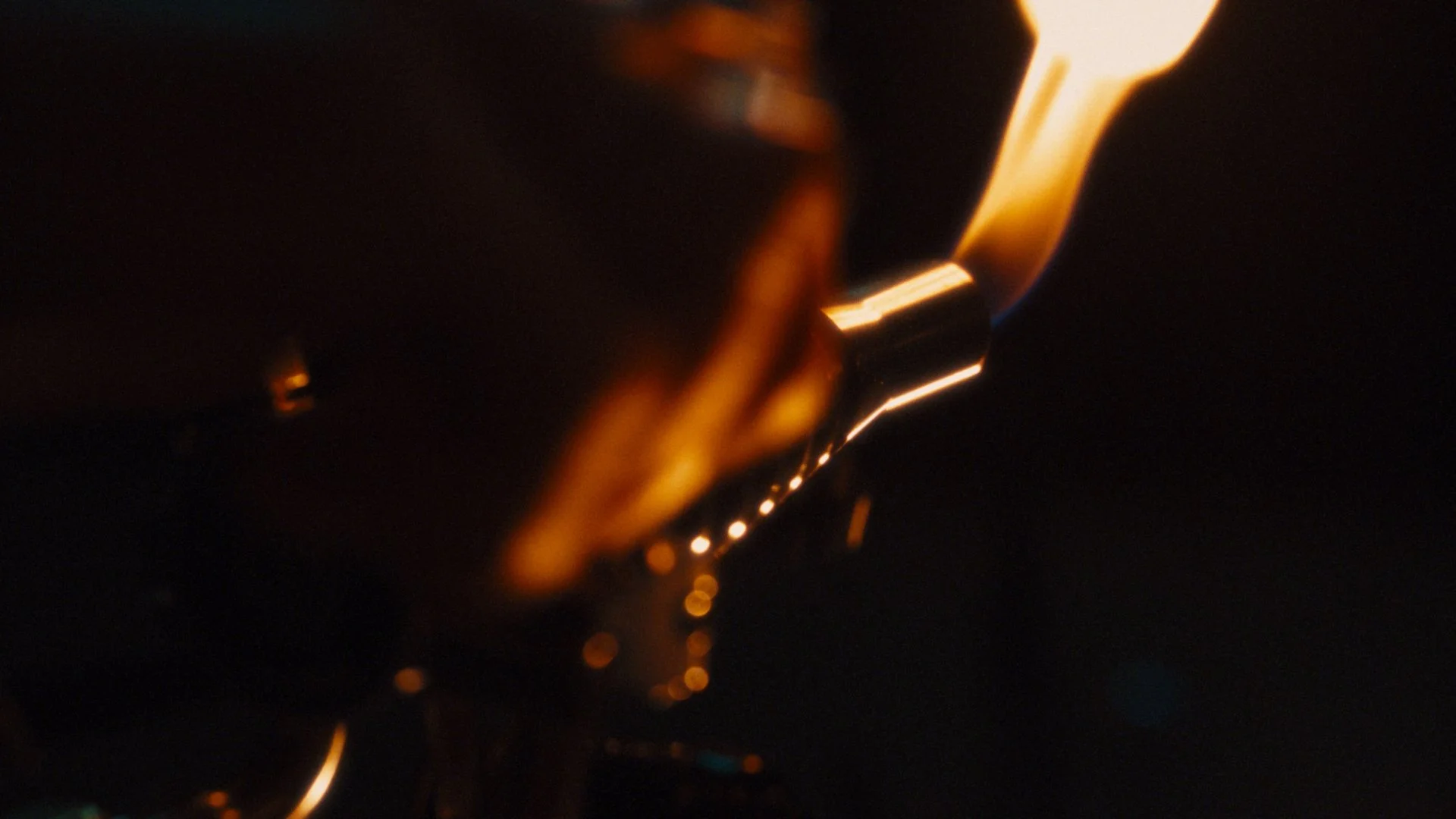 Close-up of a lighter flame with orange and yellow hues against a dark background.