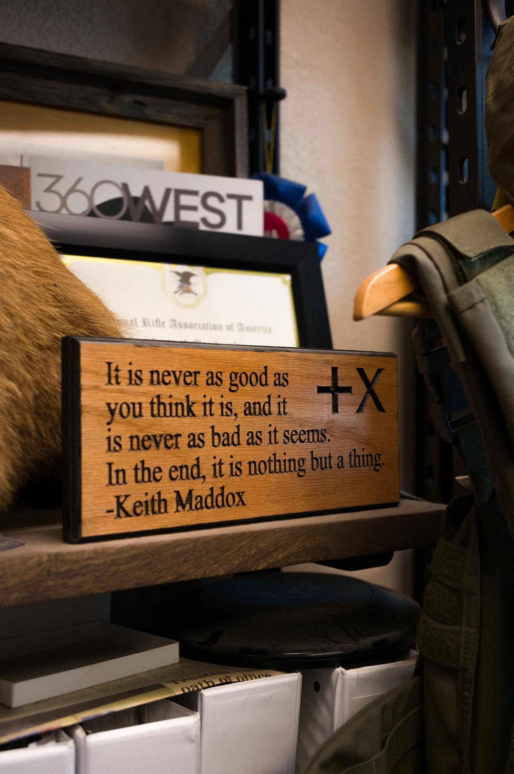 A wooden plaque with quote by Keith Maddox, saying 'It is never as good as you think it is, and it is never as bad as it seems'.