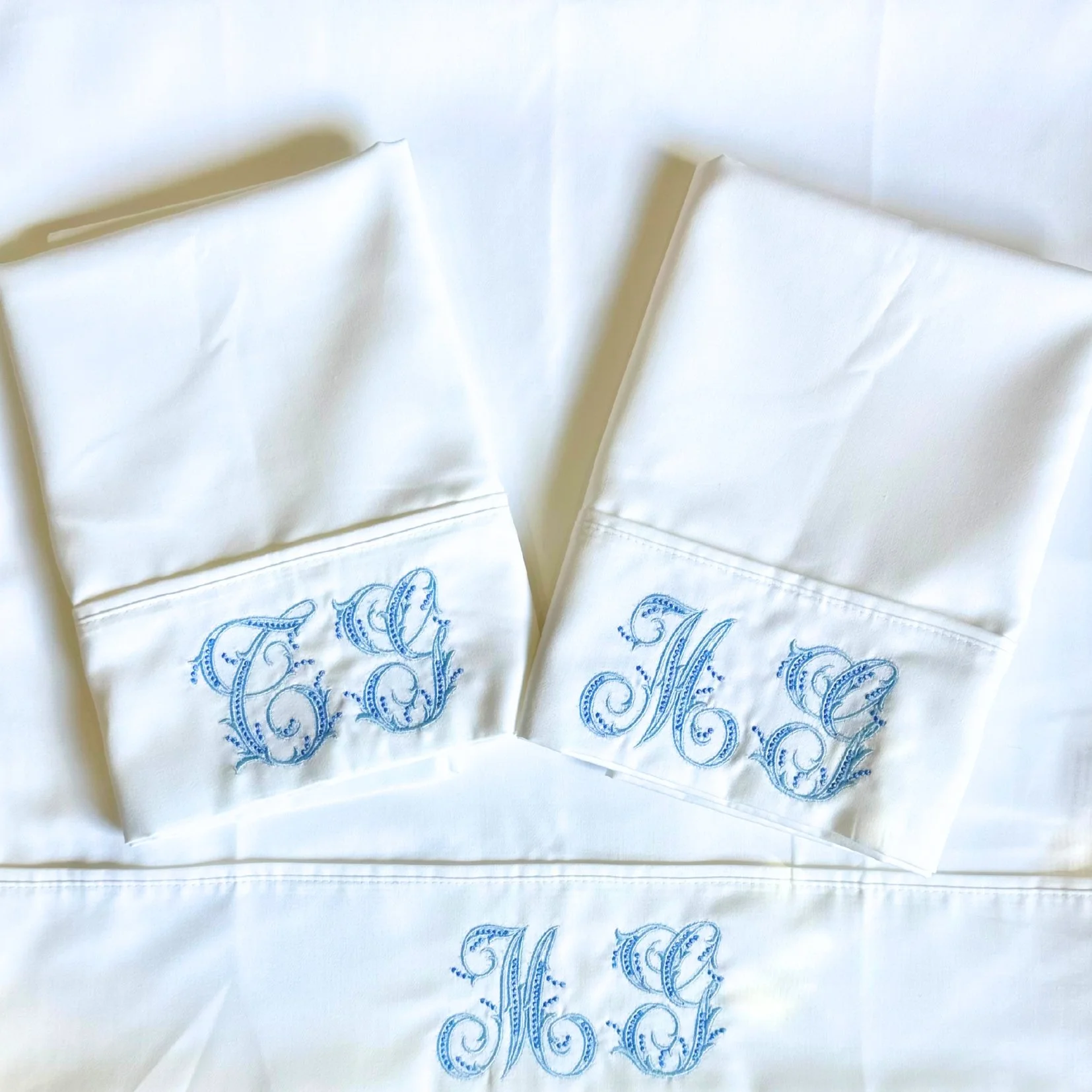 White embroidered monogrammed linens with the initials 'T' and 'H' in blue thread.