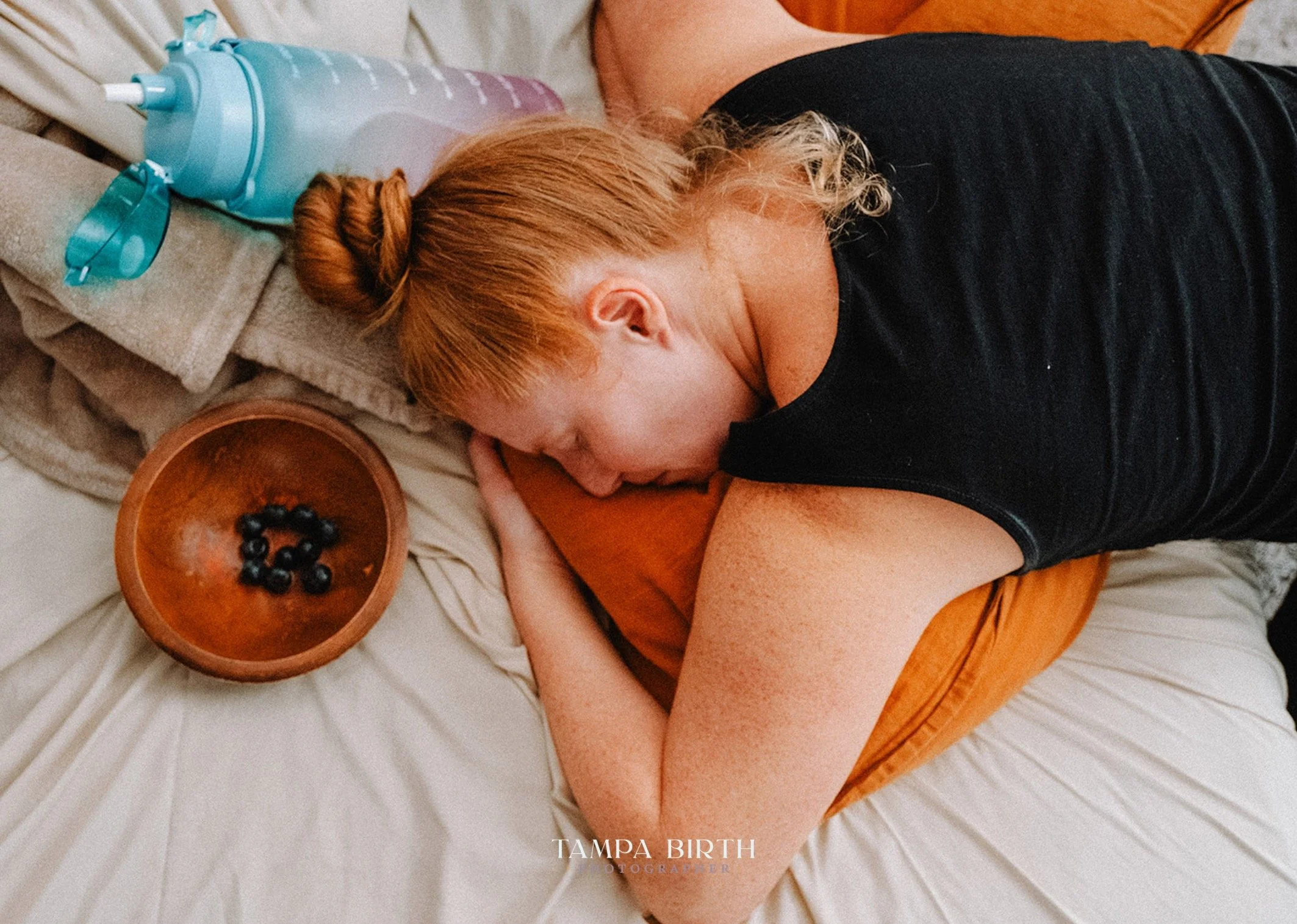 There&rsquo;s something about early labor that feels like standing on the shoreline before a wave finally breaks. Quiet. Heavy. Sacred.
The water bottle half full. The blueberries barely touched. The body folding inward to do the work only it knows h