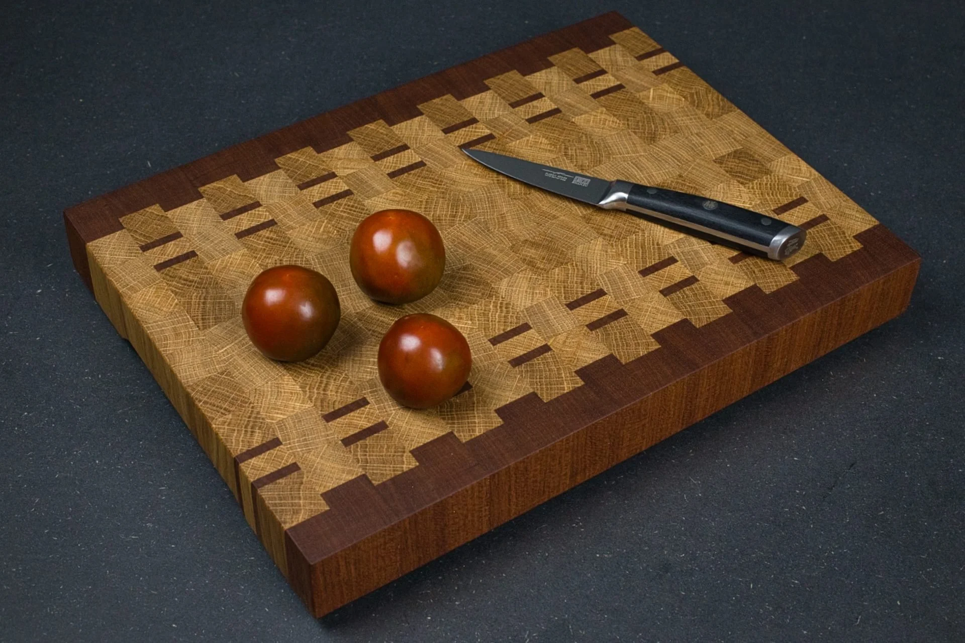 Planche à découper chêne et acajou avec un couteau et des tomates, vue en angle