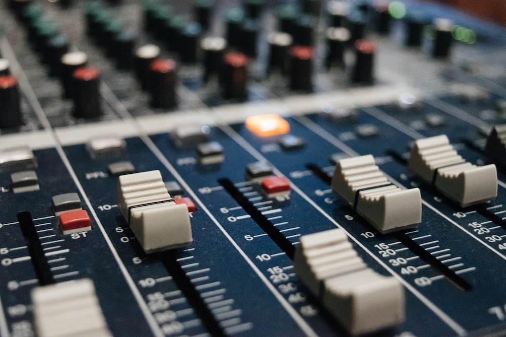 Close-up of an audio mixing console with adjustment faders, knobs, and sliders