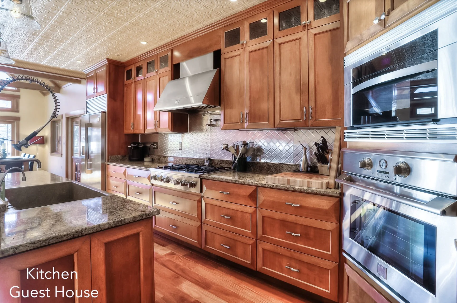 Kitchen with wooden cabinets, granite countertops, stainless steel appliances including a stove, oven, microwave, and refrigerator, and decorative tin ceiling.
