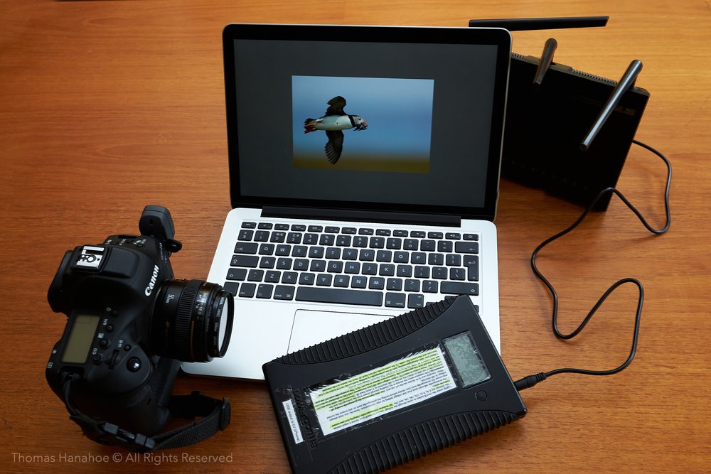 Canon camera with WFT, a laptop and a router with an attached Powergorilla battery for wireless file transmission using an infrastructure network.