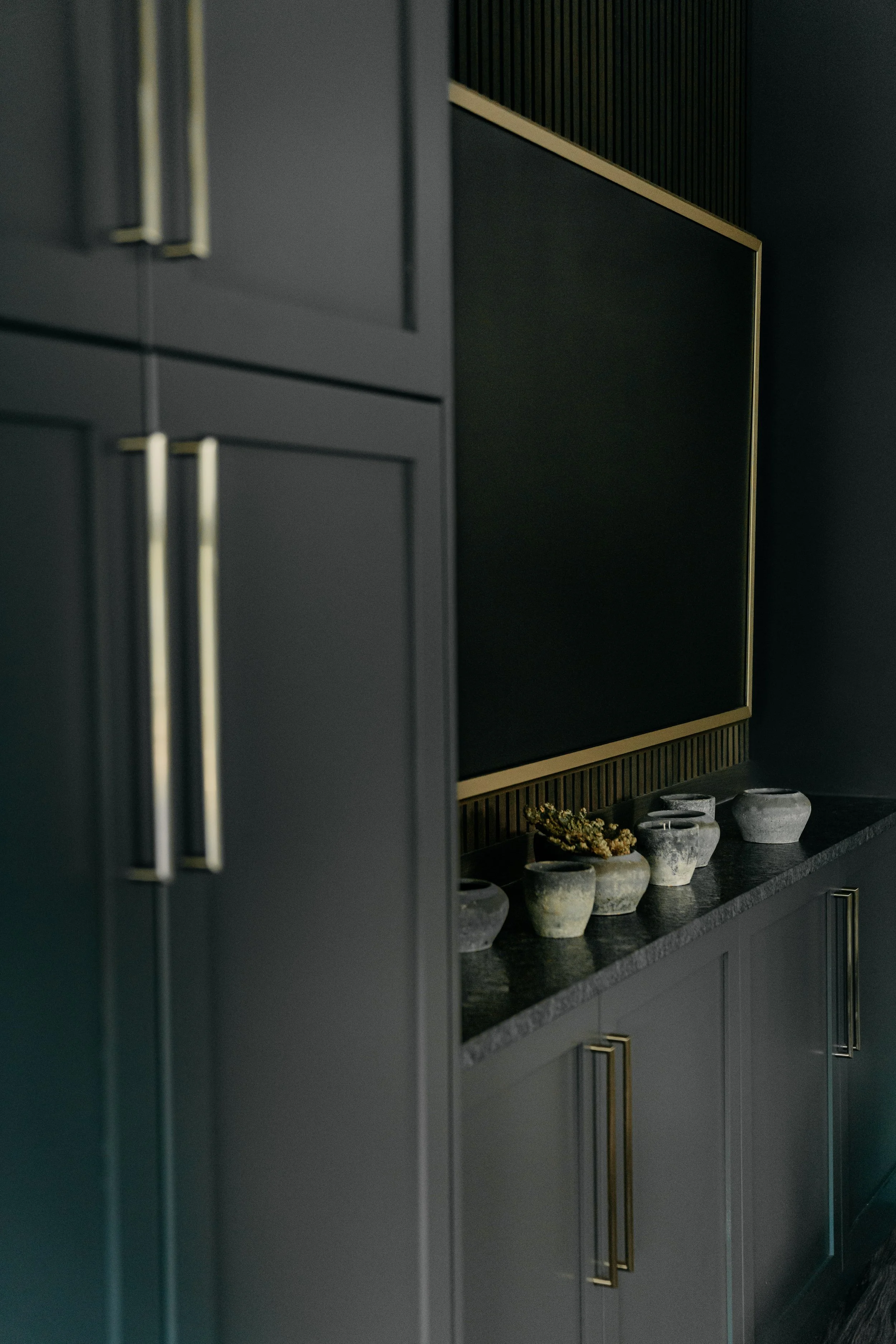 Bright open-concept living room with a beige sofa, white throw pillows, two side tables with lamps, and a view into a kitchen with white cabinetry, a wood island, and pendant lighting.