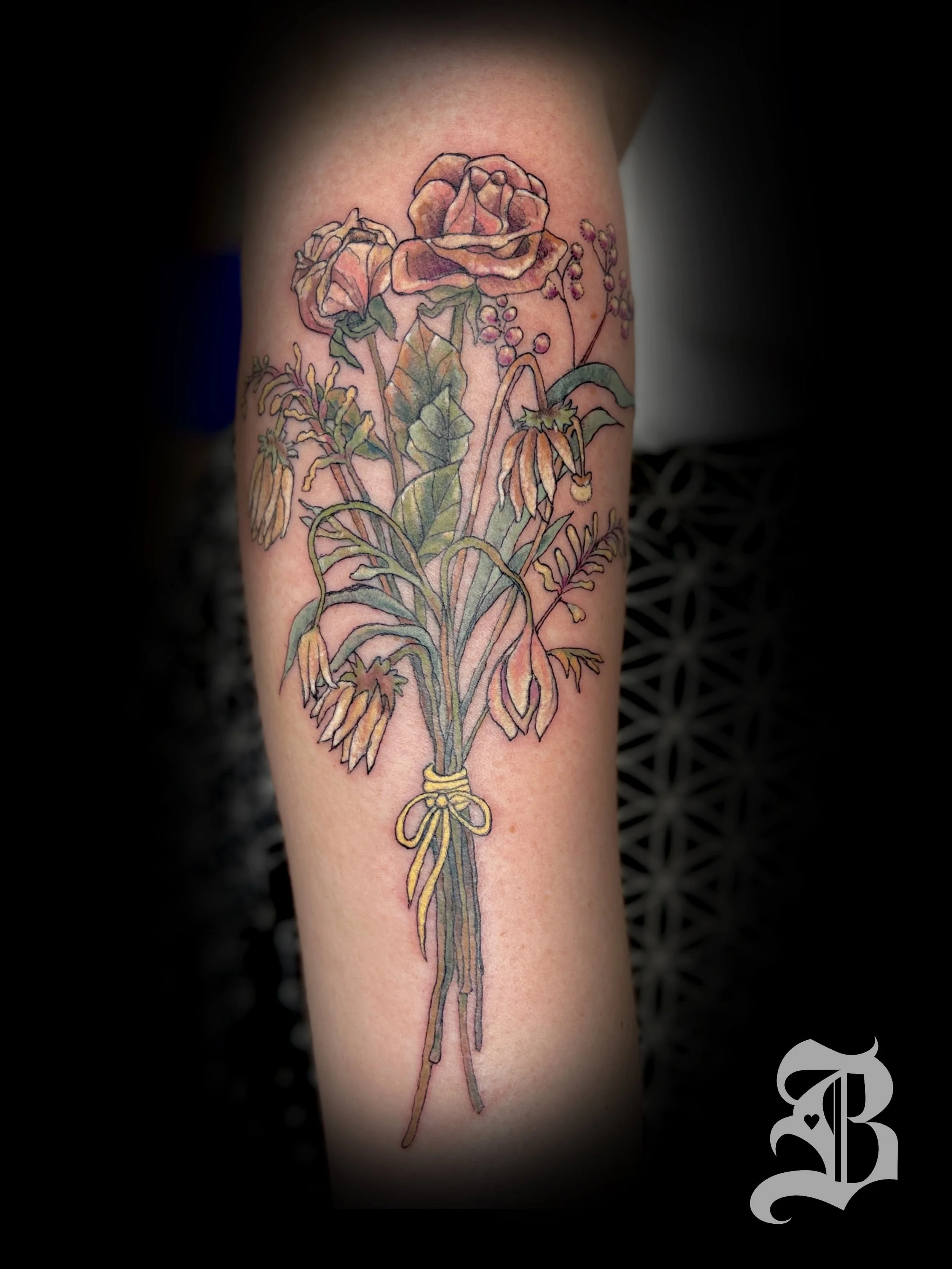 A fine line bouquet of dead flowers in full color on top of the forearm.