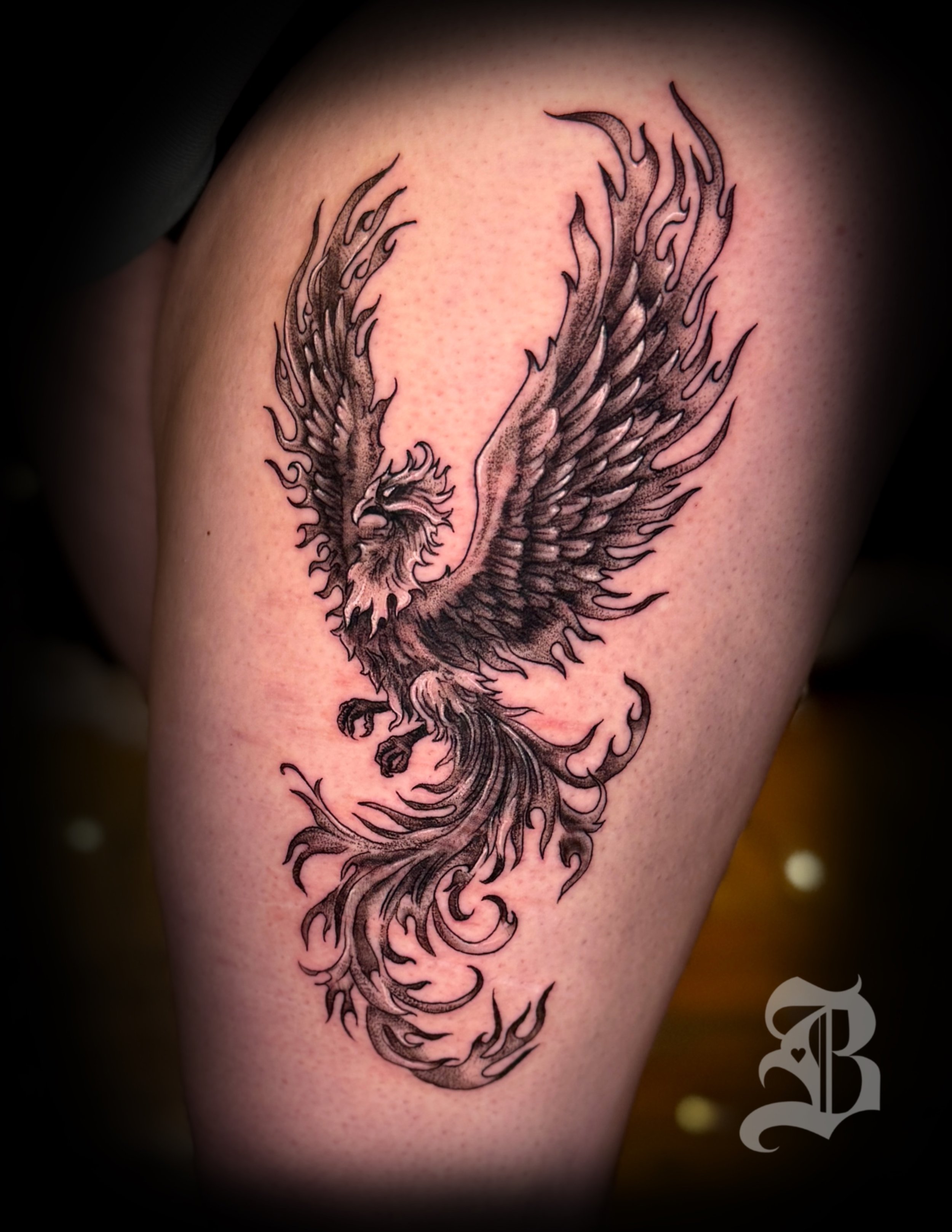 A black and gray tattoo of a phoenix with outstretched wings on someone's upper arm by Binx inks.