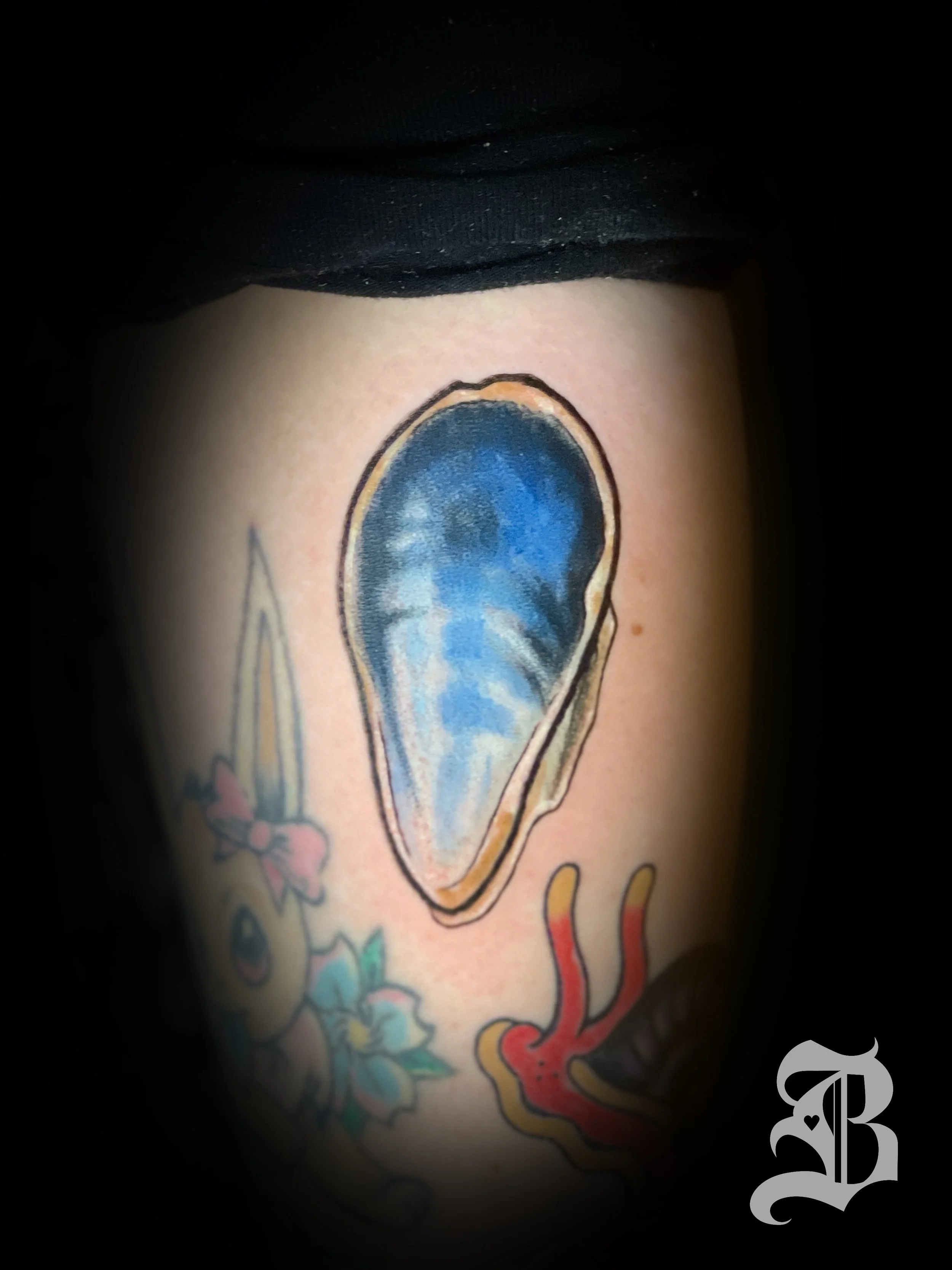 Small muscle shell colored arm tattoo.