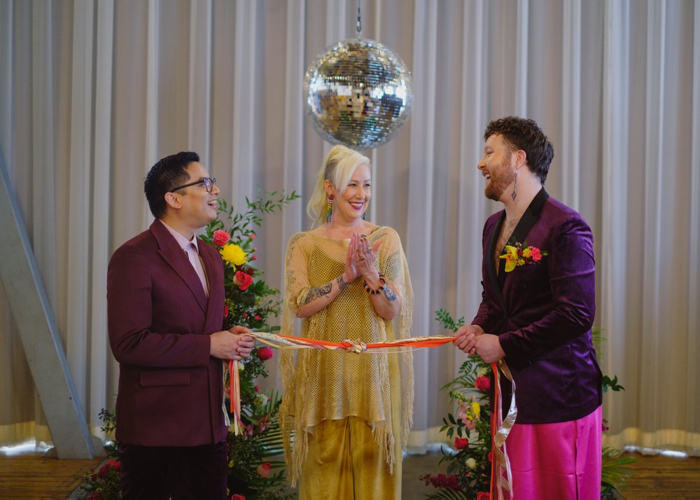  Two grooms and their officiant have “tied the knot” and completed the hand fasting ceremony. 