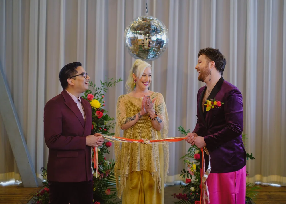  Two grooms and their officiant have “tied the knot” and completed the hand fasting ceremony. 