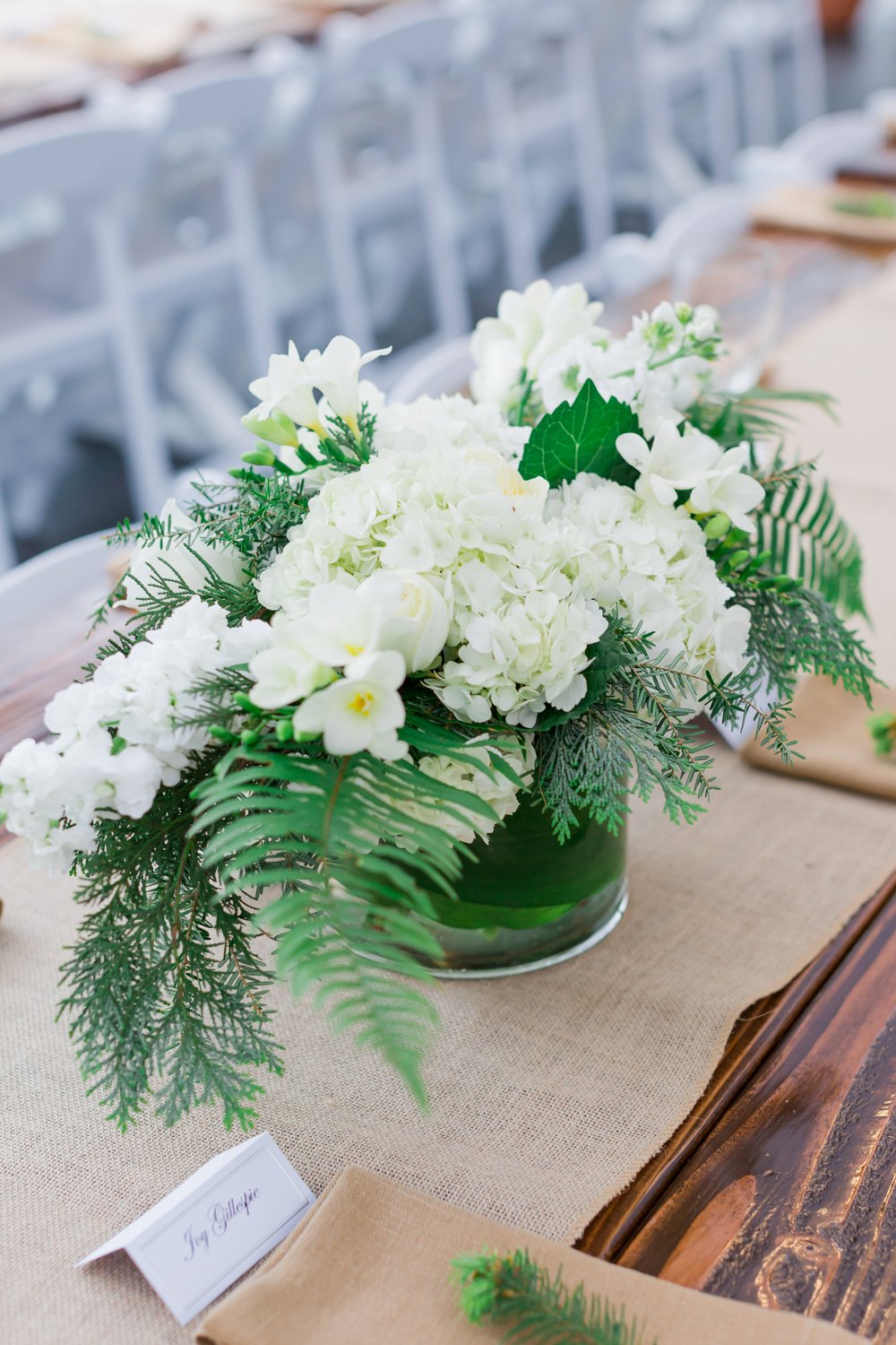  A floral centerpiece featuring greenery and white flowers. 
