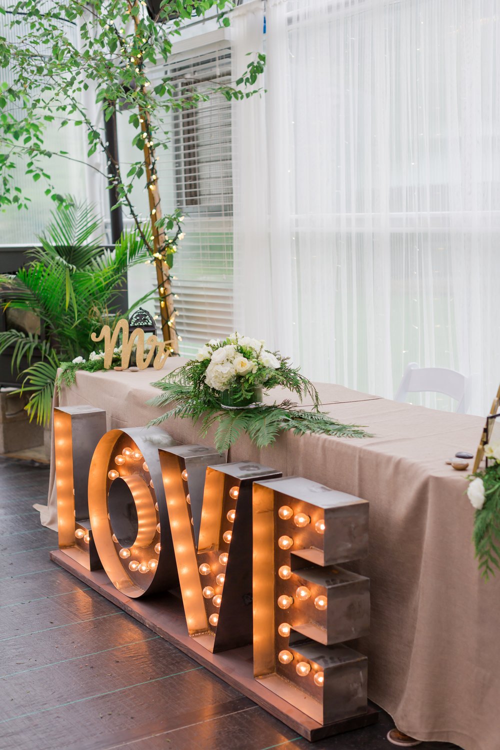  A sweetheart table with marquee letters spelling “LOVE” in front of it. 