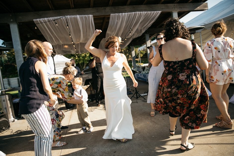  A bride in a white dress is dancing with guests at her wedding. 