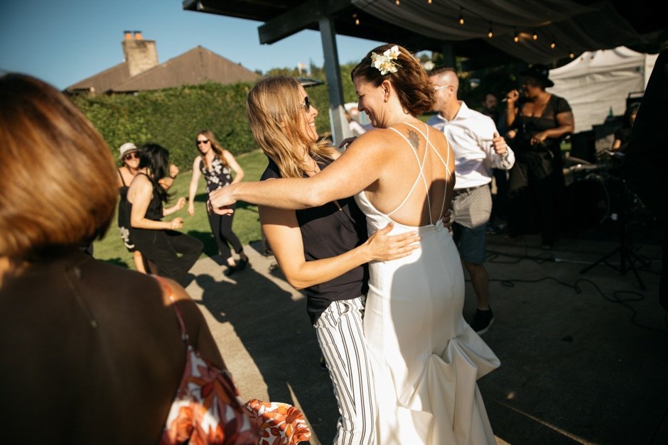  Two brides embrace in a slow dance on the dance floor at their wedding. 