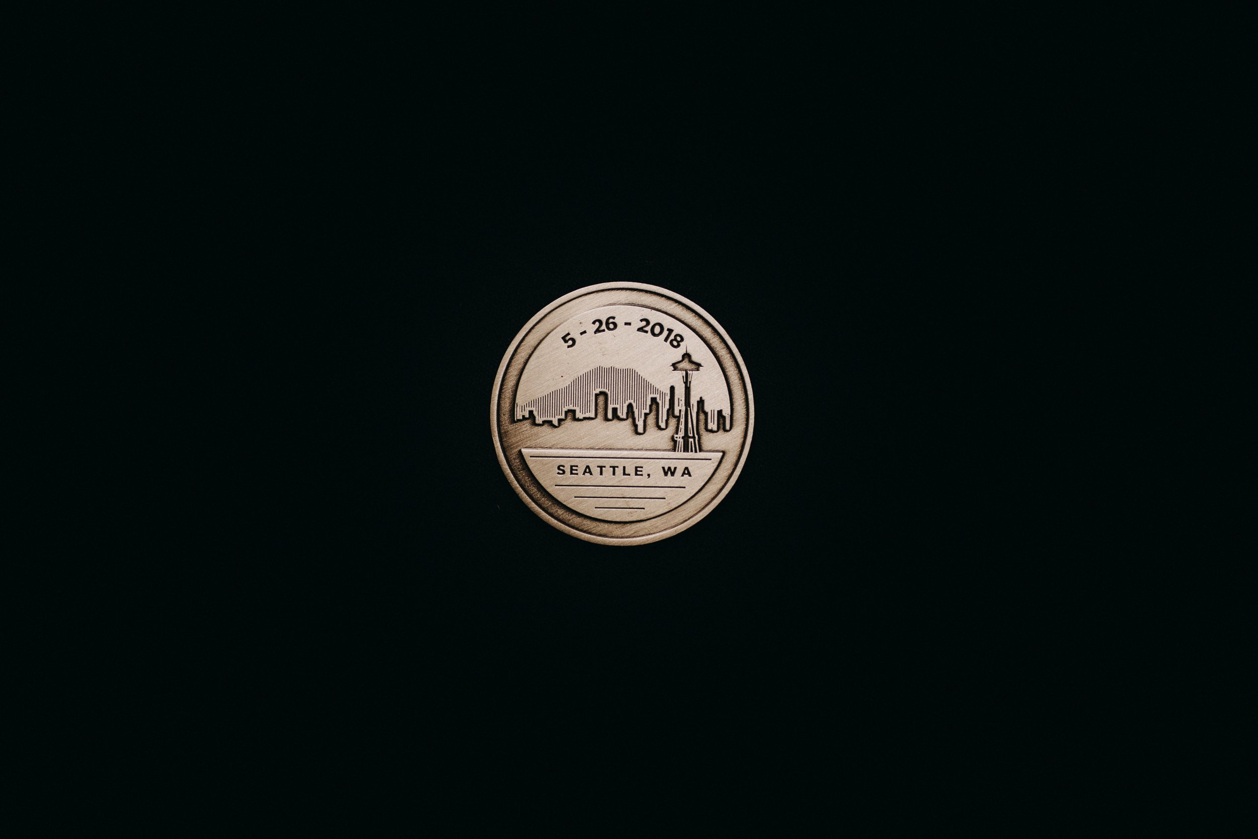 The back of the grooms’ custom medallion. There is imagery of the Seattle skyline with mountains and it reads “5-26-2018 Seattle, WA” 