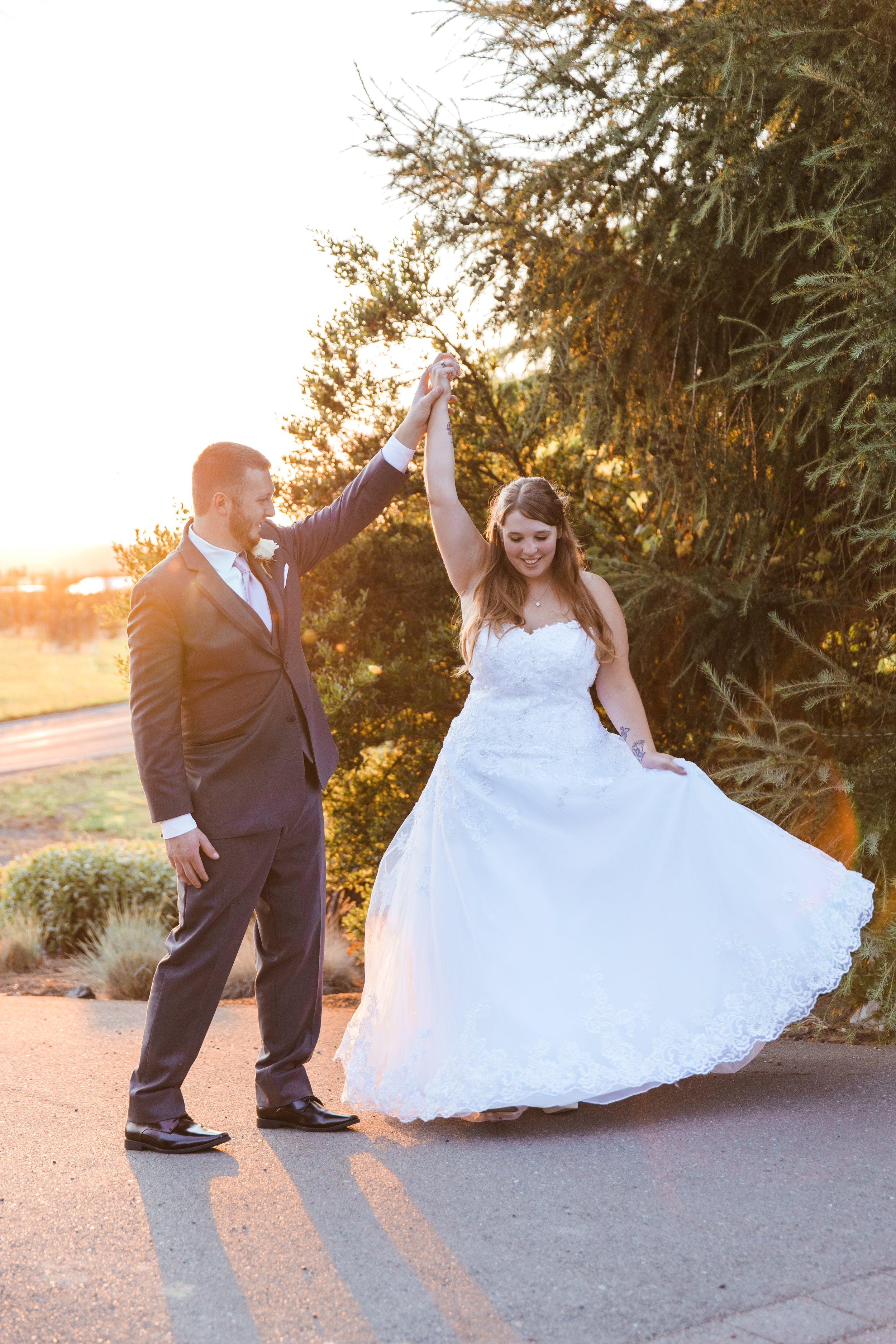  A bride and groom pose at golden hour. The bride is twirling and her dress flares. 
