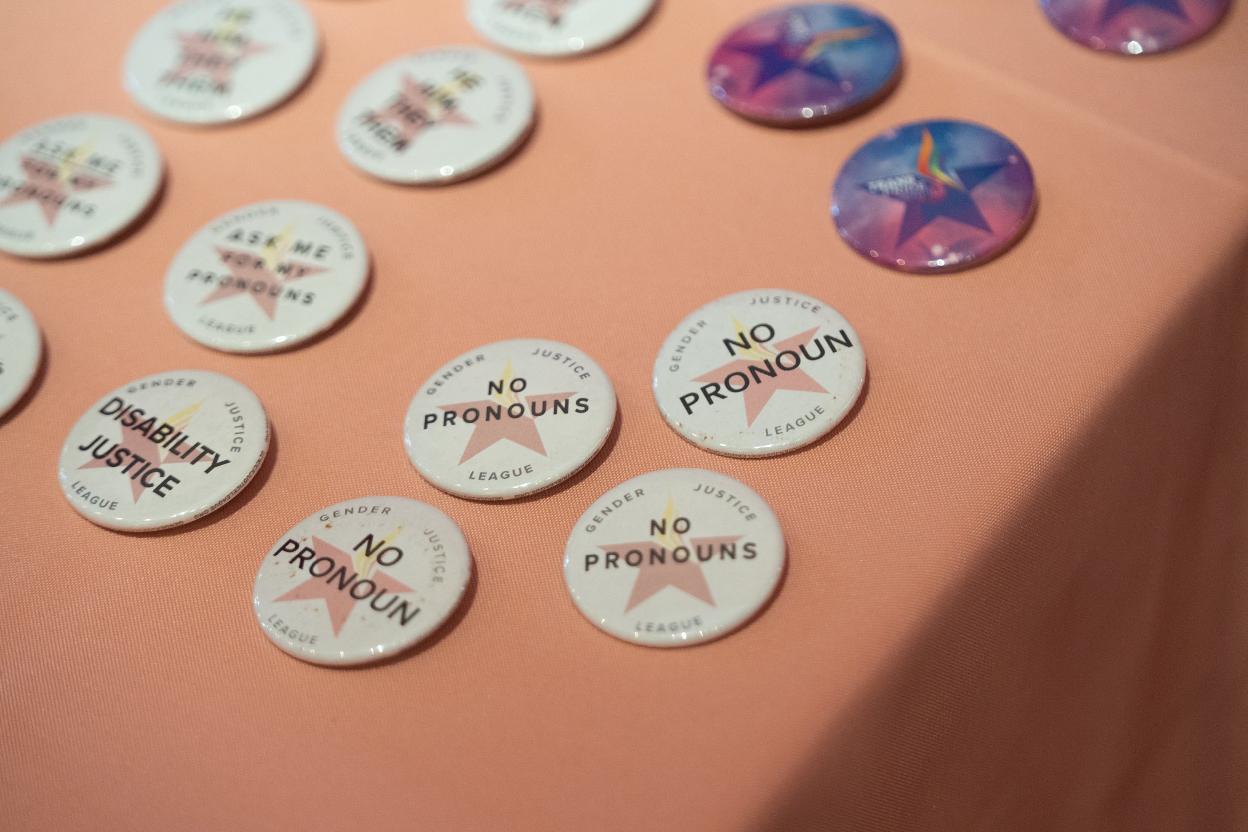  A close up of pronoun pins, the most visible option says “no pronouns” 