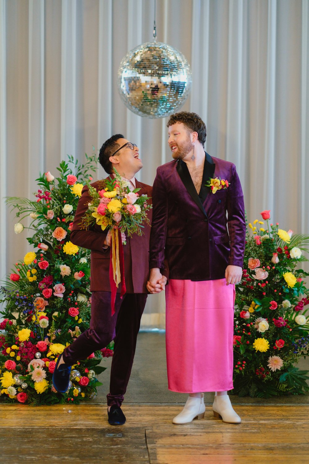  Two grooms stand at their wedding altar, sharing a celebratory smile after their ceremony. 