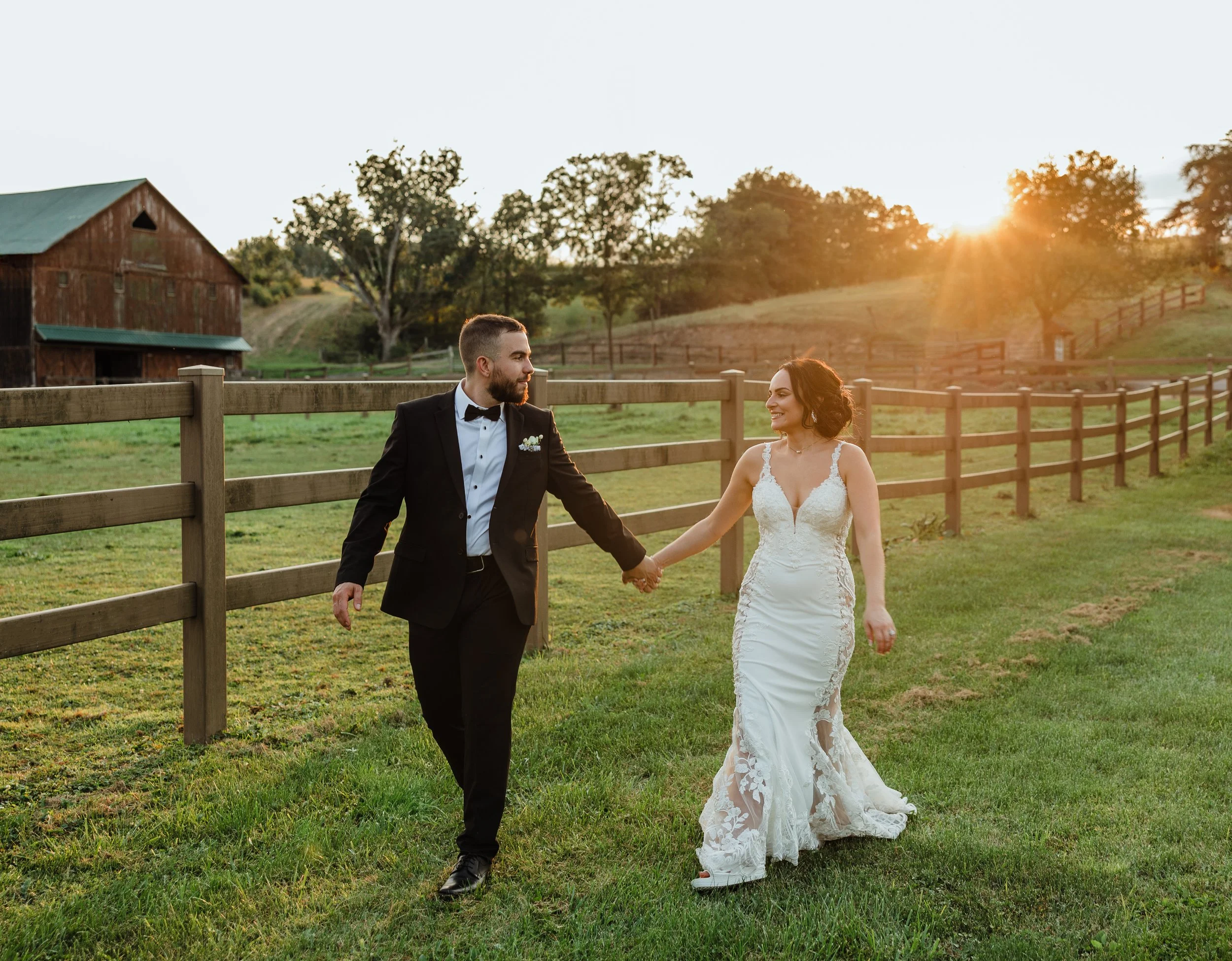 Wedding photographer captures Steven and Angela walking hand in hand with barn backdrop at Creekside Resort, Clearville PA