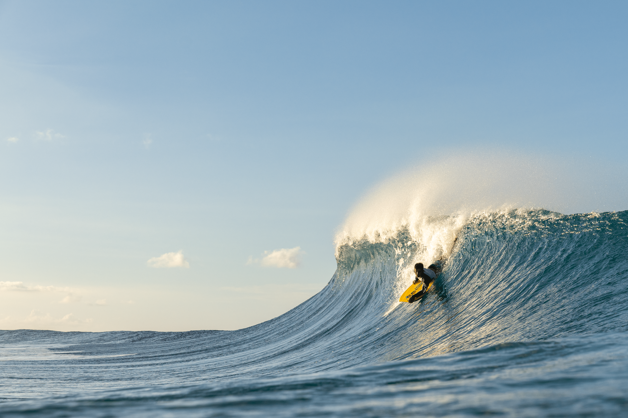 Person surfing on a large wave in the ocean during daylight.