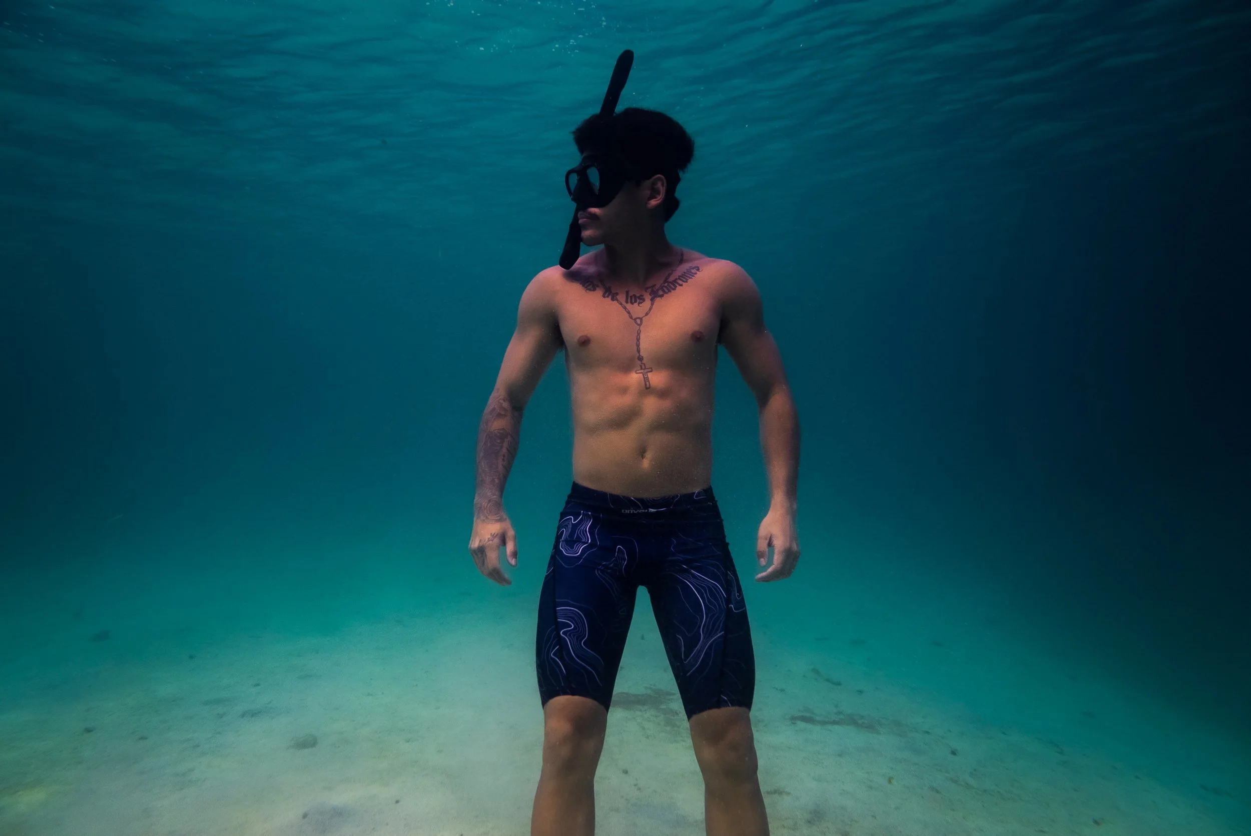 Product photography featuring a model underwater in a clear ocean.