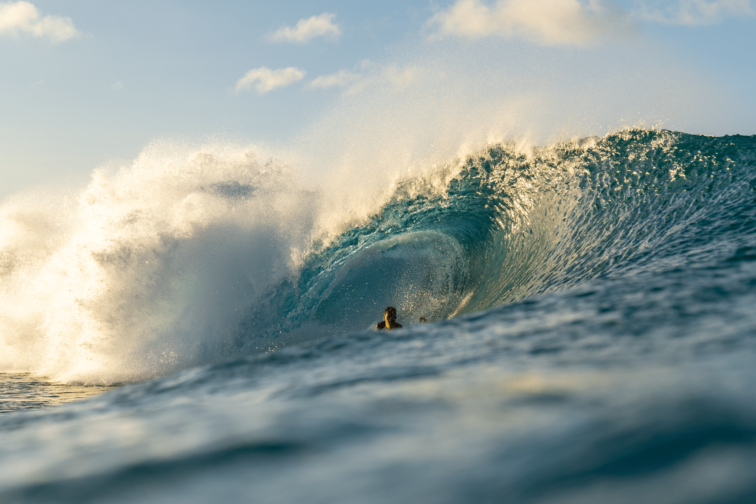 A person surfing on a large wave in the ocean during daylight.