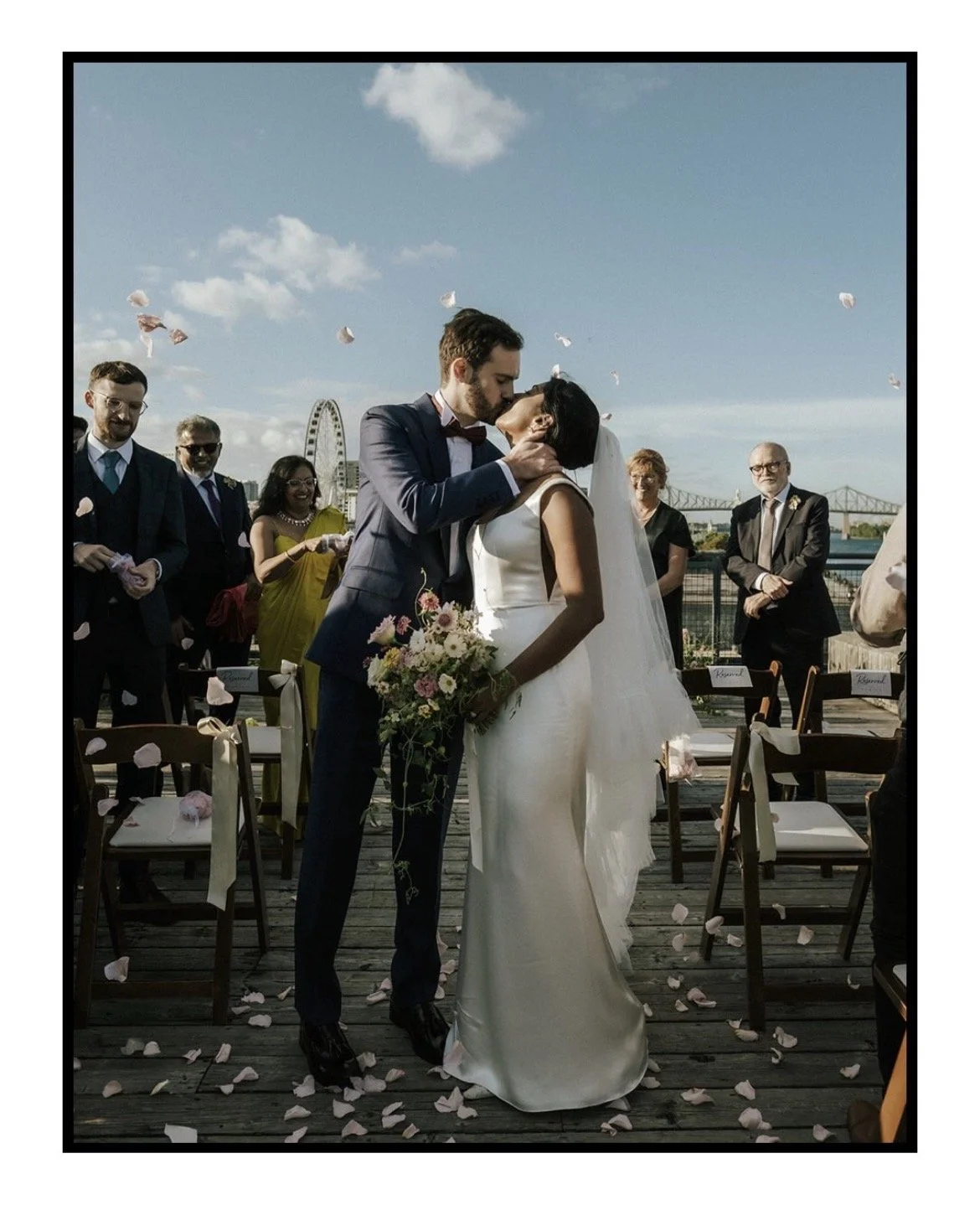 Bride and groom kissing at the end of the aisle with bride wearing a custom made ruffle tulle veil