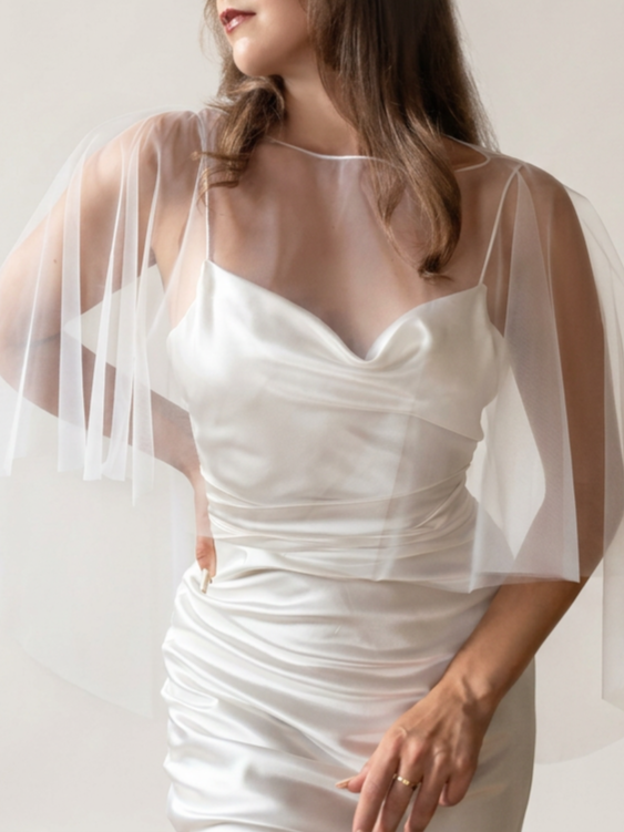A bride wearing a soft tulle wedding cape