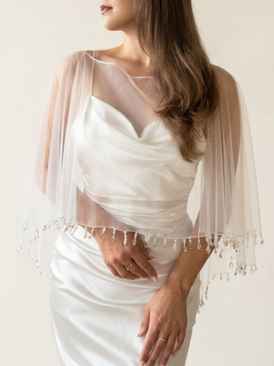 A bride wearing an ivory tulle wedding cxape with pearl and crystal nead droplets