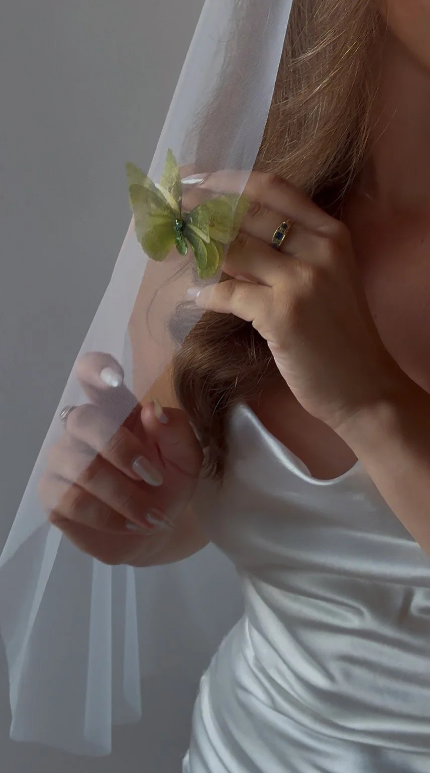 A 3-layered green bridal butterfly veil weight on a veil with a bride