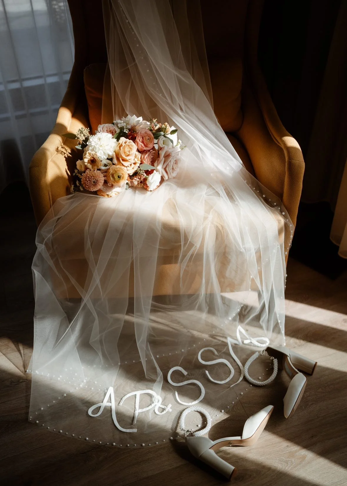 A bridal veil on a chair with the bride and grooms initals