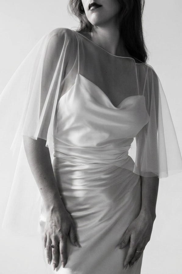 A black and white image of a bride wearing an off-white tulle bridal cape