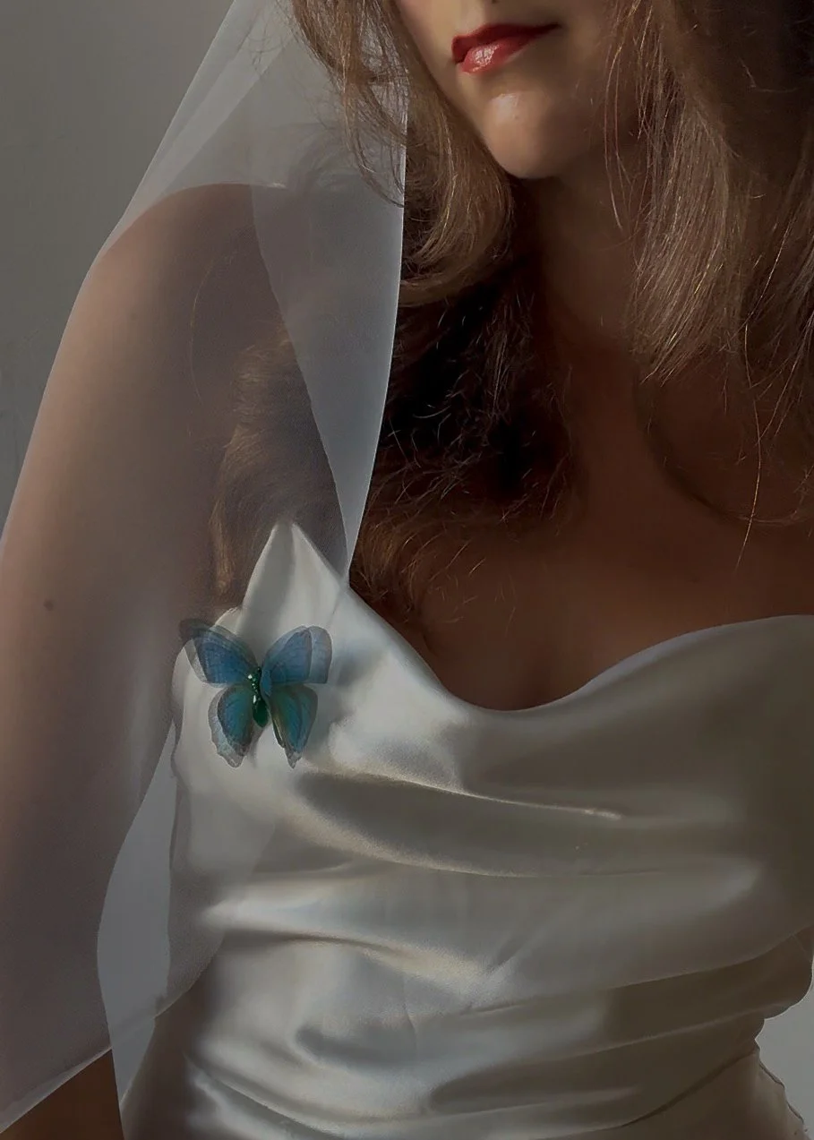 A blue butterfly veil weight attached to a white wedding veil