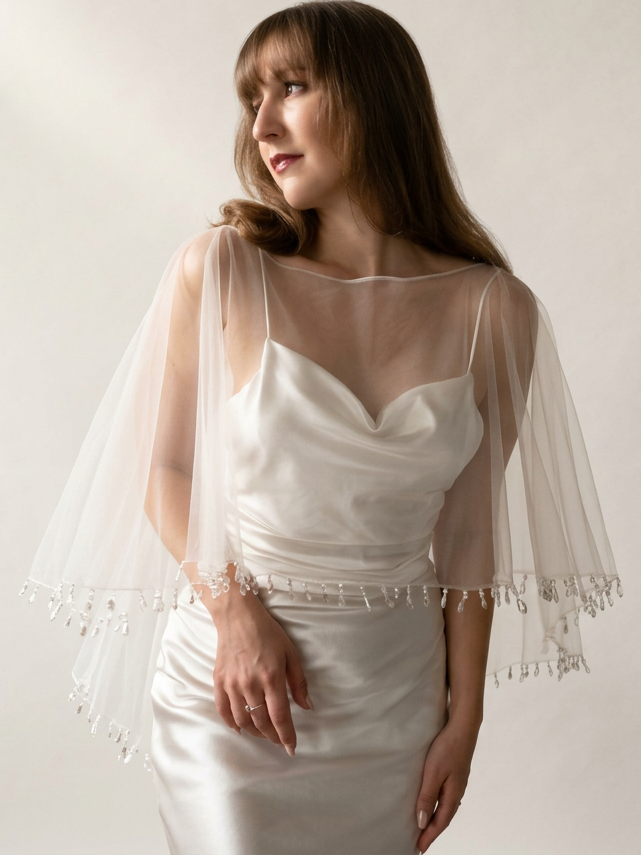A bridal spinning around wearing an ivory bridal shawl with crystal and pearl droplets along the edge
