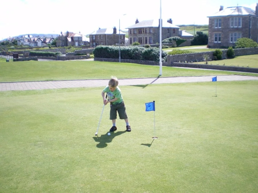 Little boy in green t-shirt on the putting green at Machrihanish.