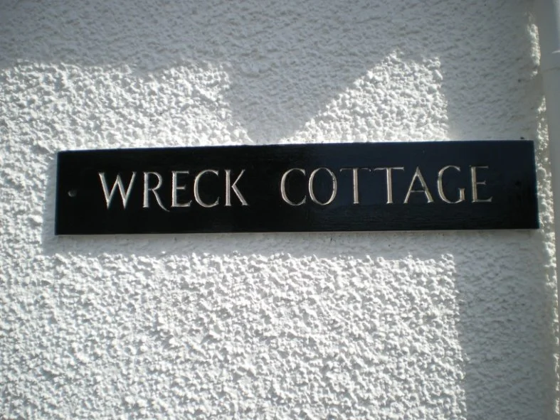 Slate wall sign reading 'Wreck Cottage'.