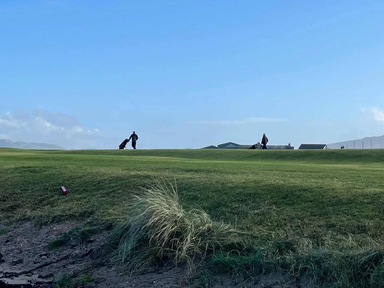 Golfers silhouetted with a blue sky behind.