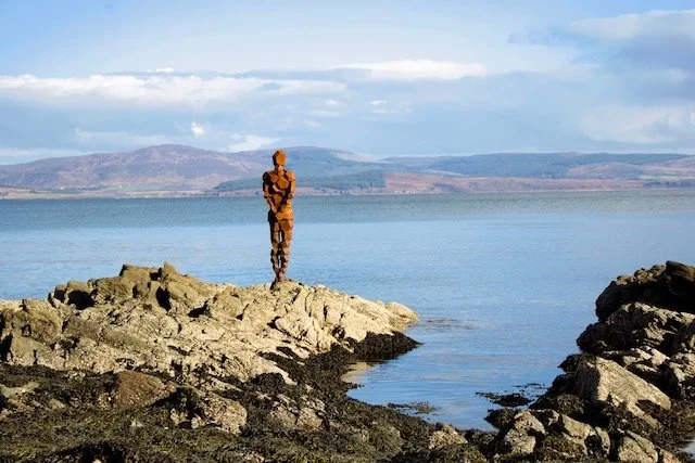 Anthony Gormley sculpture of a man standing looking out across the sea at Carradale.