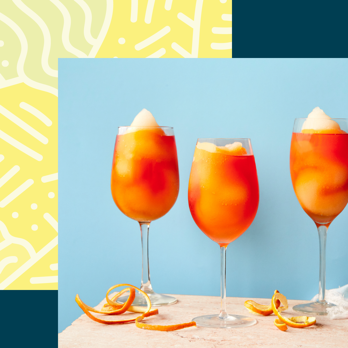  Three orange slush cocktails are framed by a bright pattern. 