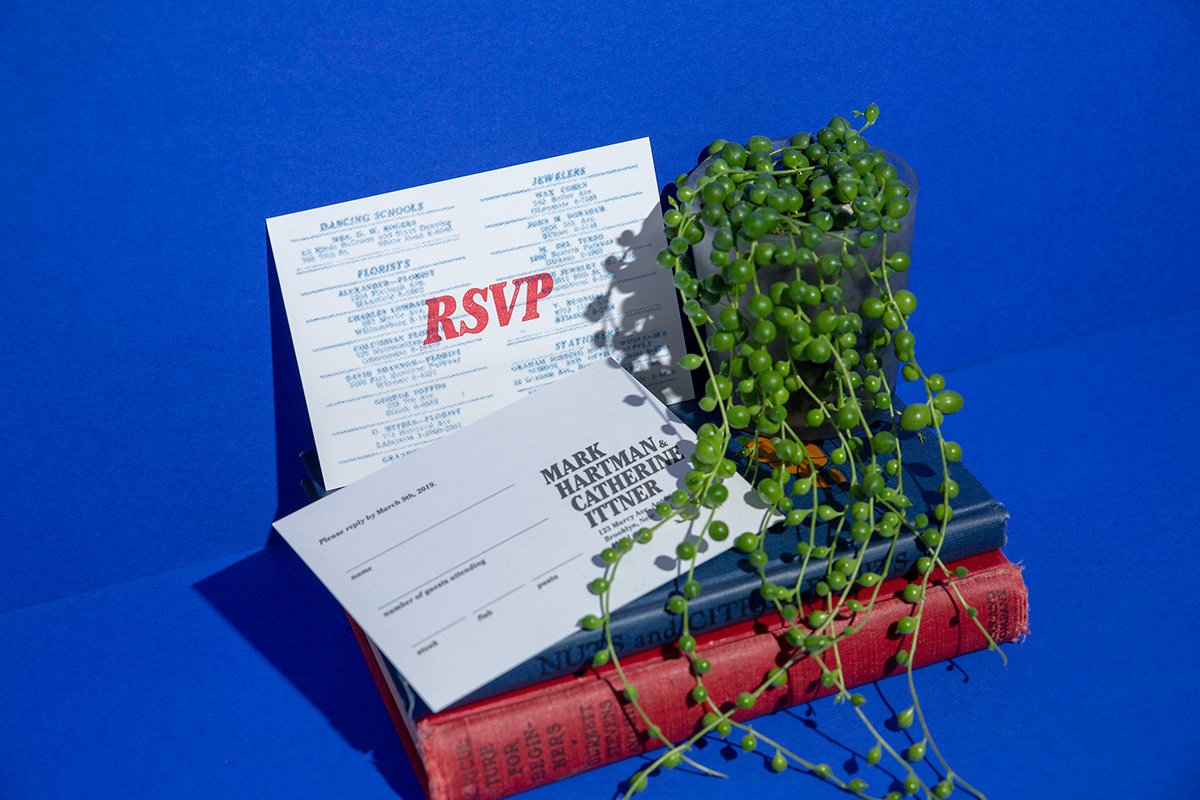  An RSVP card with red and blue ink overprinted on one another, photographed on a blue background 