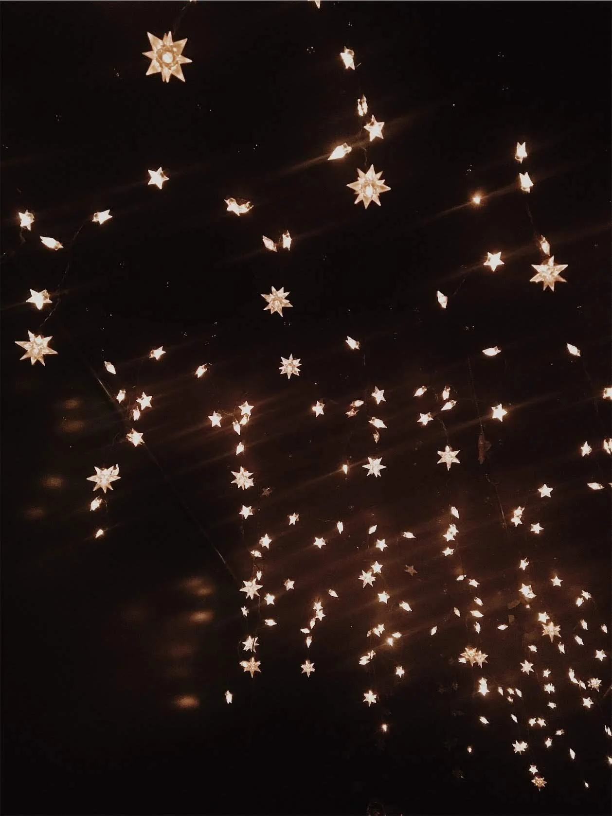 A dark ceiling is adorned with numerous small, glowing star-shaped lights