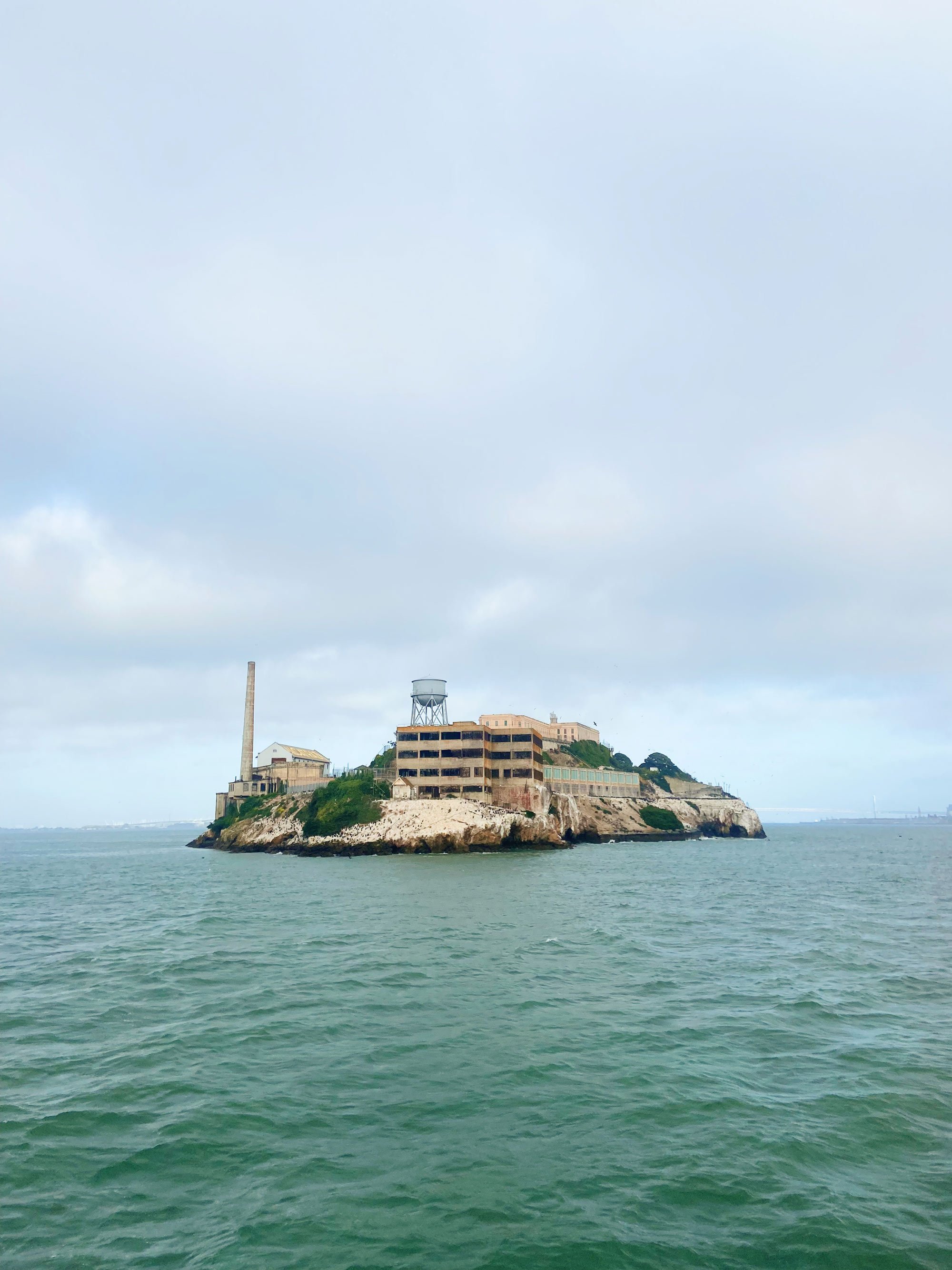 Distant view of Alcatraz Island in San Francisco Bay, featuring rocky shoreline and historical prison buildings