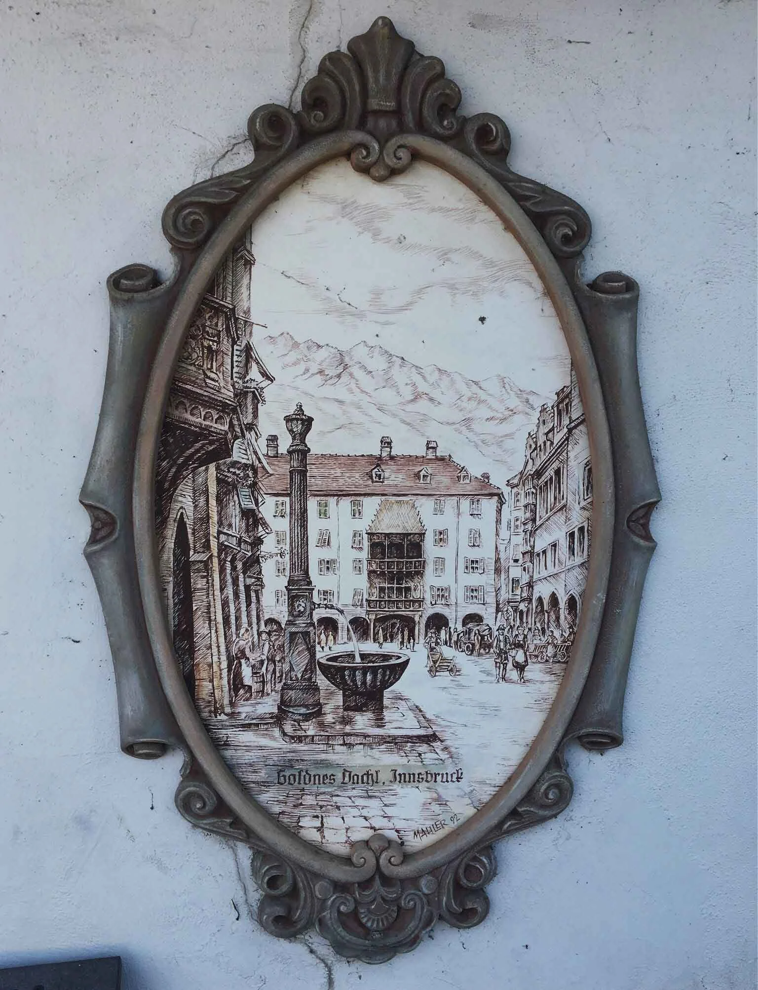 An oval-shaped framed artwork depicting an old European street scene. "Goldnes Dachl, Innsbruck" is written at the bottom.