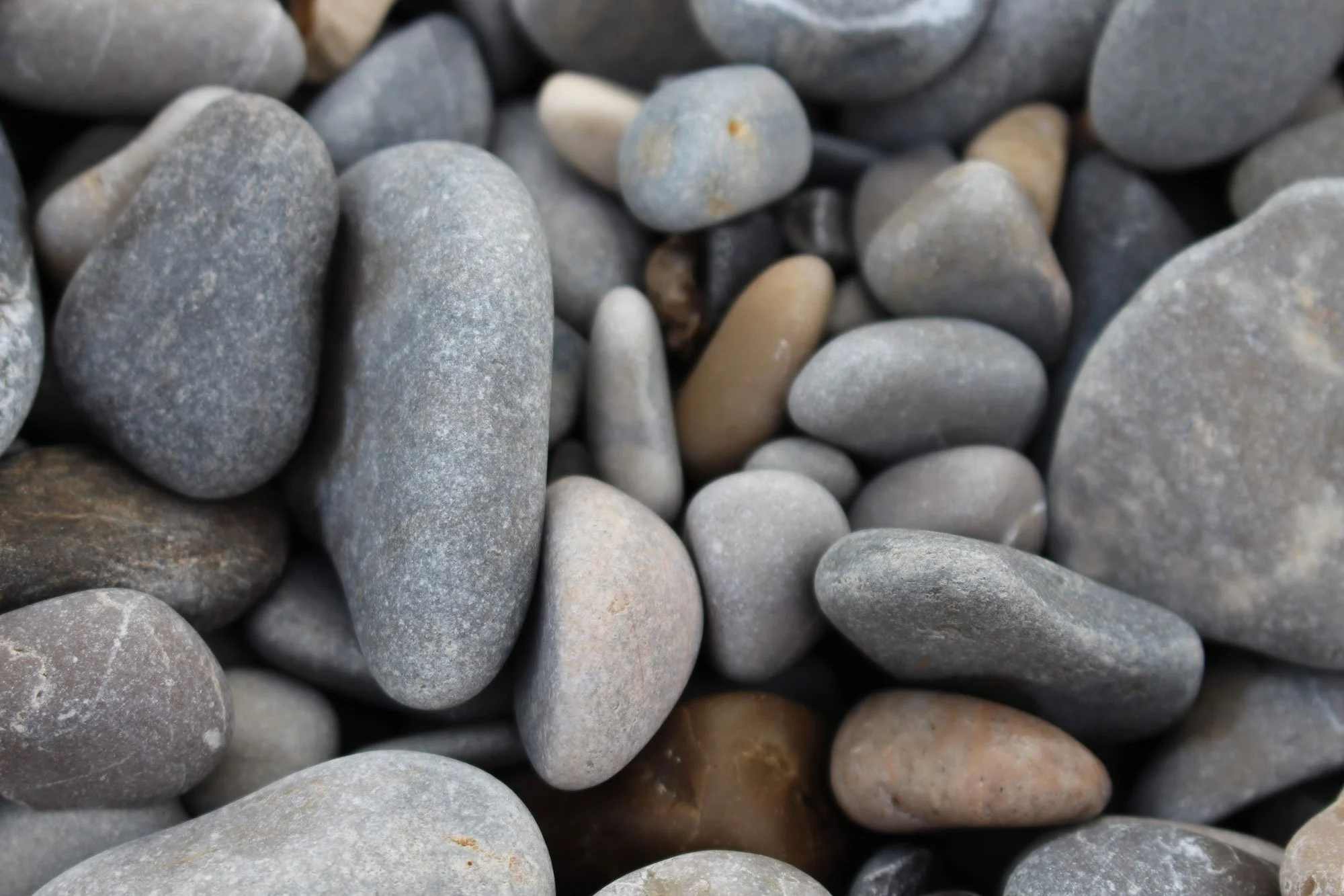 A close-up image showing a variety of smooth, rounded pebbles and stones tightly packed together