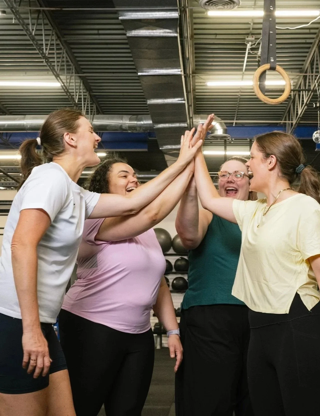 Allison and crew of women inside a gym high fiving with positive expressions on their faces.