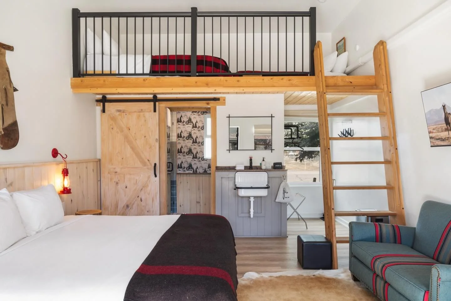 Studio King Loft Spotlight: Old West charm meets modern amenities and design, complete with a king bed + additional 2 lofted twin beds accessible via ladder. A Pendleton loveseat for additional seating, bespoke bathroom wallpaper, lofty ceilings and 