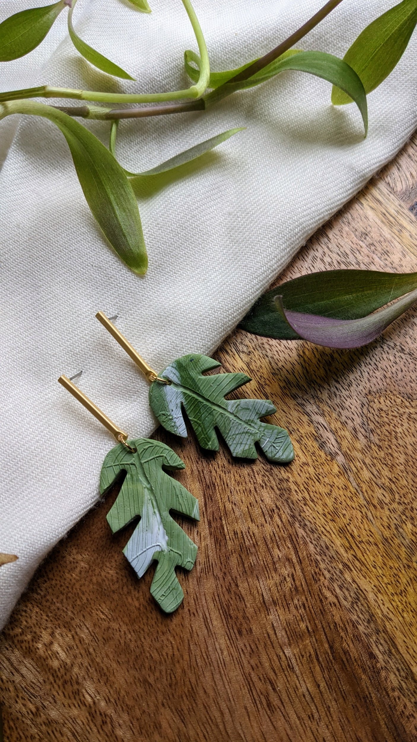 Handcrafted polymer clay earrings. Gold straight post with green and white textured leaf. All components are gold plated, silver plated, or stainless steel with sensitive ears in mind.